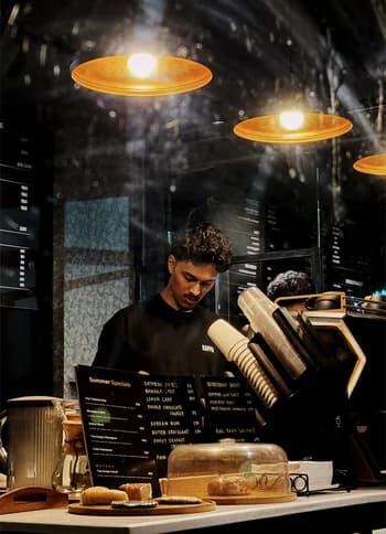 A barista working under warm pendant lights