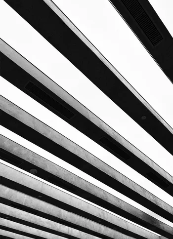 A concrete facade in black and white, its balconies cutting the frame in diagonal bands